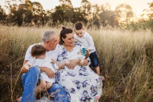 A family sitting in a grass field at sunset