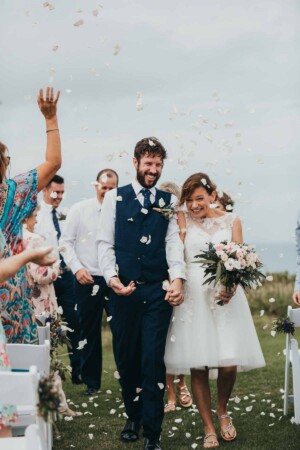 Guests throw rose petals over newlyweds