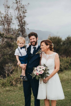 A bride and groom holding their page boy