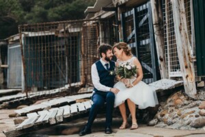 Newlyweds laugh near the Sandon Point boat sheds