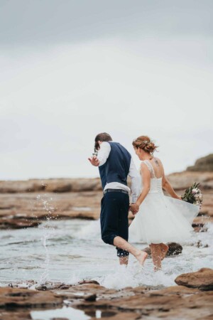 A married couple jumping waves at Sandon Point