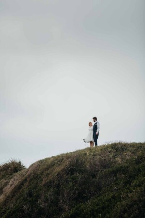 A married couple stand on cliffs at Sandon Point