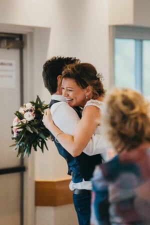 A bride hugs her groom as they enter the reception
