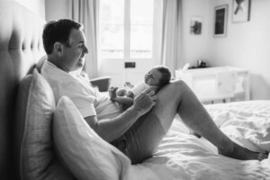 A new dad holds his newborn son in his lap