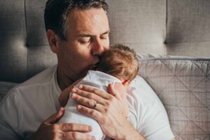 A new dad kisses his newborn son on the head