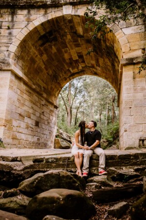 An engaged couple share a kiss under Lennox Bridge