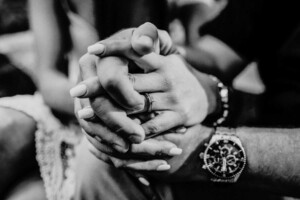A couple holding hands and show off their engagement ring