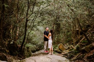 A couple embrace on the edge of a forest gully