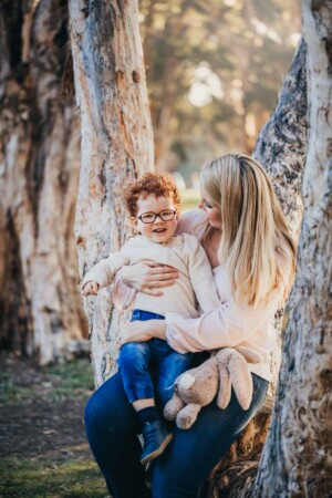 A mum snuggles her little boy as the sun sets behind them