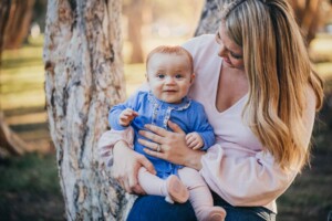 A mum snuggles her little girl as the sun sets behind them