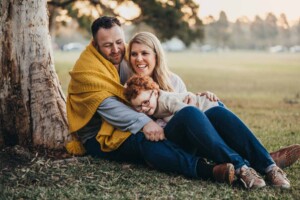 A couple cuddle their son under a blanket in Sydney