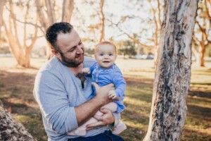 A dad cuddles his little girl as the sun sets behind them