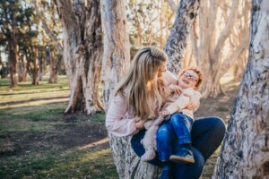 A mum tickles her little boy as the sun sets behind them
