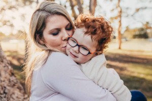 A mum kisses her little boy as the sun sets behind them