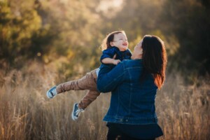 A mum spins her son around during a photo session at sunset