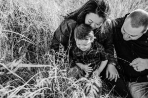 A father tickles his son's cheek with a piece of grass at sunset