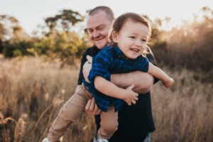 A dad whooshes his son around during their photo session at sunset