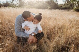 A father kisses his sons cheek as the sun sets behind them