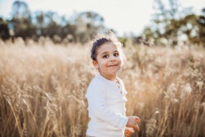 A little boy smiles up at his parents during a family photo session