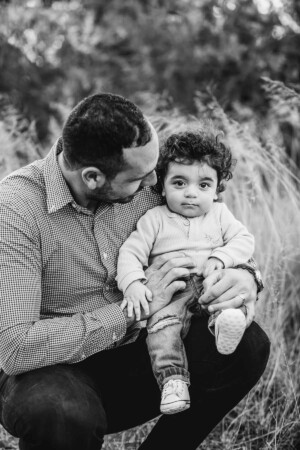 A father holds his baby boy in his lap for a photograph