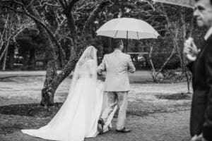 Newlyweds exit their Sylvan Glen wedding ceremony under an umbrella