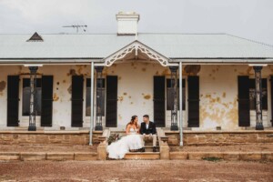 Gledswood Wedding - A bride and groom sit on the steps of the homestead