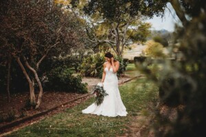 Gledswood Wedding - Wedding portrait, bride looking at her wedding bouquet in the gardens of Gledswood Estate