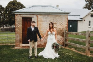 Gledswood Wedding - newlyweds hold hands as they stand against a brick wall