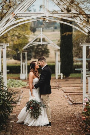 Gledswood Wedding - A groom hugs his bride beneath on the the archways in the gardens of Gledswood estate