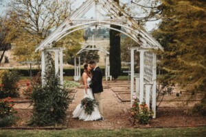 Gledswood Wedding - A groom hugs his bride beneath on the the archways in the gardens of Gledswood estate