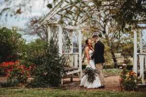 Gledswood Wedding - A groom hugs his bride beneath on the the archways in the gardens of Gledswood estate