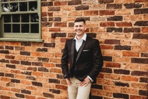 Gledswood Wedding - groom stands against a brick wall