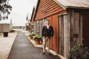 Gledswood Wedding - A groom leans against a rustic wooden door