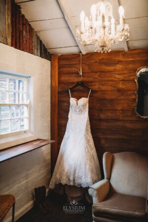 Gledswood Wedding - A brides dress hangs on the wooded wall in the bridal suite at Gledswood