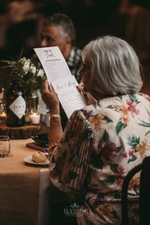 Gledswood Wedding - A wedding guests reads through the games list at the wedding reception