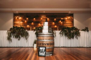 Gledswood Wedding - Wedding cake sits on a wine barrel in front of the bridal table at the reception
