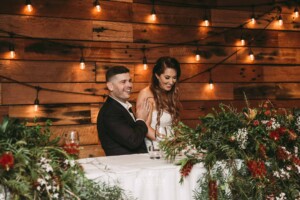 Gledswood Wedding - A bride and groom laugh as they listen to speeches at the wedding reception