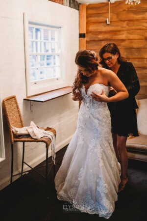 Gledswood Wedding - The mother of the groom helps the bride into her wedding gown