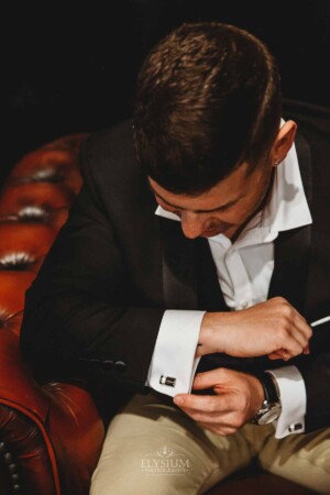 Gledswood Wedding - A groom admires his cufflink while preparing for the wedding