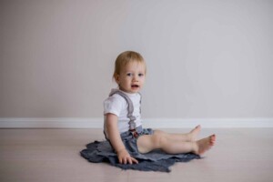 Little boy sitting on a blue felt matt in a natural light studio