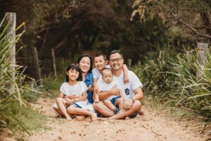 A family sit cuddling on a sandy beach path
