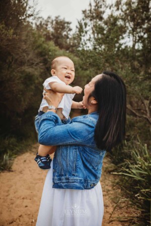 A mother lifts her little boy above her in the bush