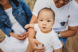 Parents sit cuddling their baby boy in their laps