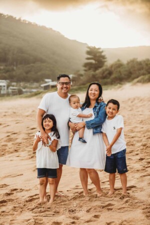 A family cuddle together standing on a sandy beach