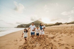 A family run along the sandy beach at sunset