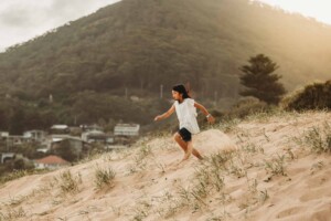 A little girl races down a beach sand dune at sunset