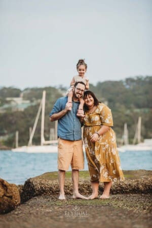 Family Photographer - A little girl sits on her dads shoulders at Balmoral Beach