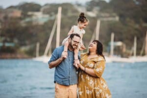 Family Photographer - A little girl sits on her dads shoulders at Balmoral Beach