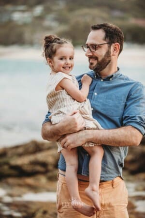 Family Photographer - A father hugs his little girl at Balmoral beach