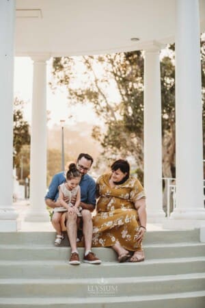 Family Photographer - Parents sit on the Balmoral Rotunda steps cuddling their little girl